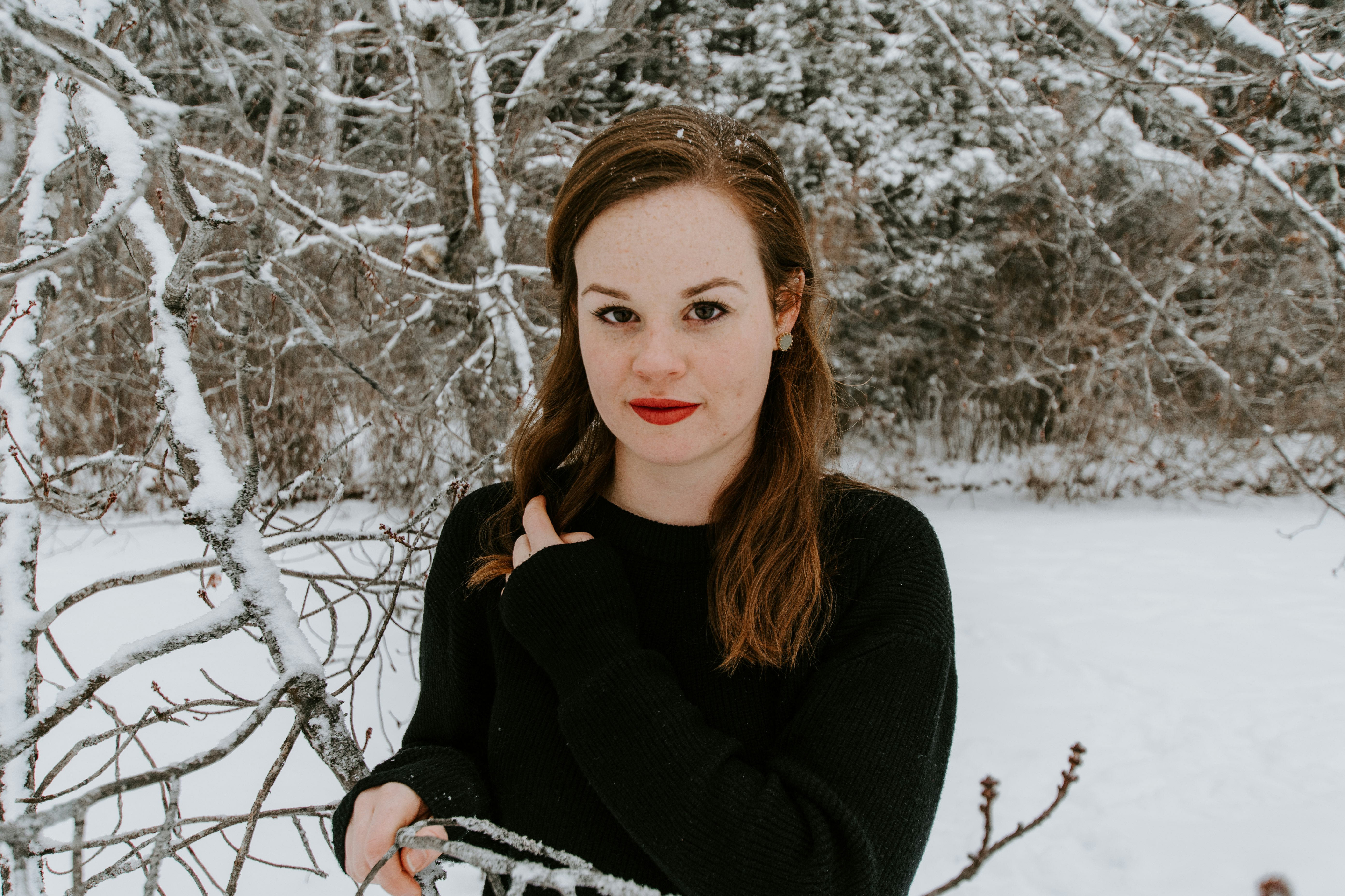 woman wearing black sweater holding tree branch